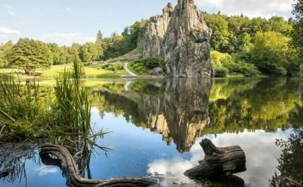 Bild von einem See, in dem sich ein markanter Felsen spiegelt